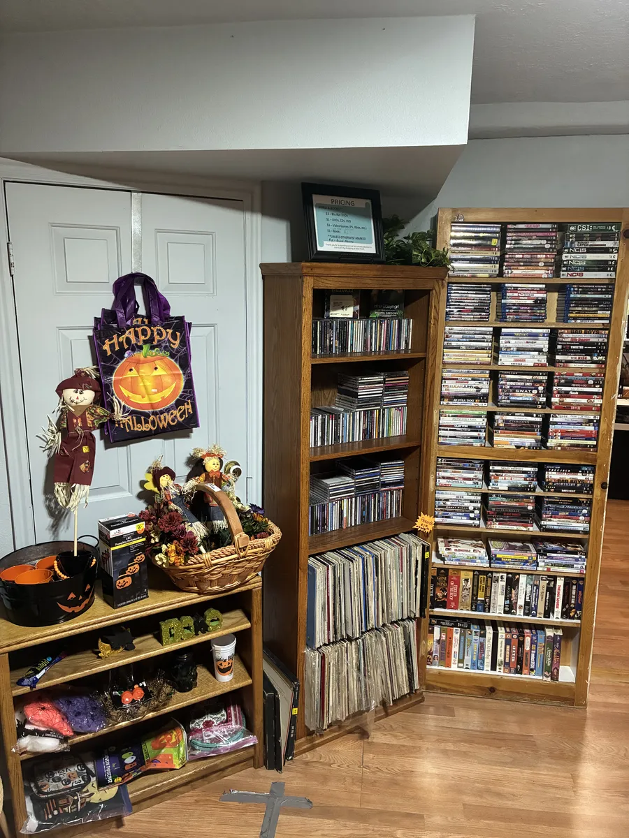 Shelves of CDs, records and DVDs beside Halloween decorations at BAM Thrift store