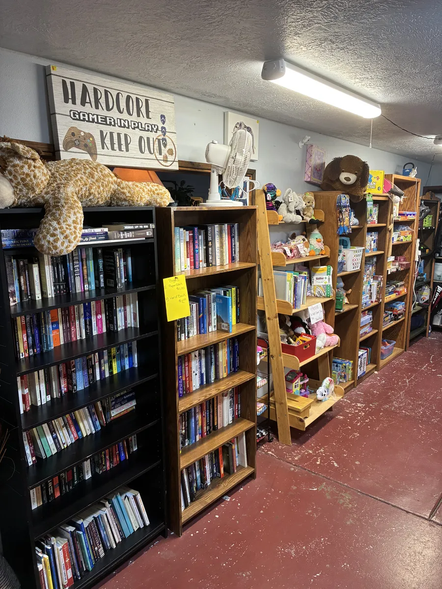 Shelves of books and movies alongside stuffed animals and toys at BAM Thrift store