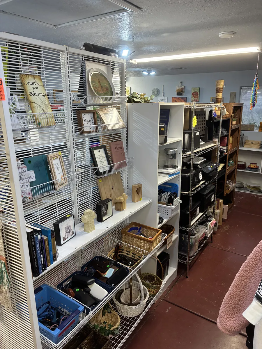 Picture frames, baskets and shelves of household goods inside BAM Thrift store