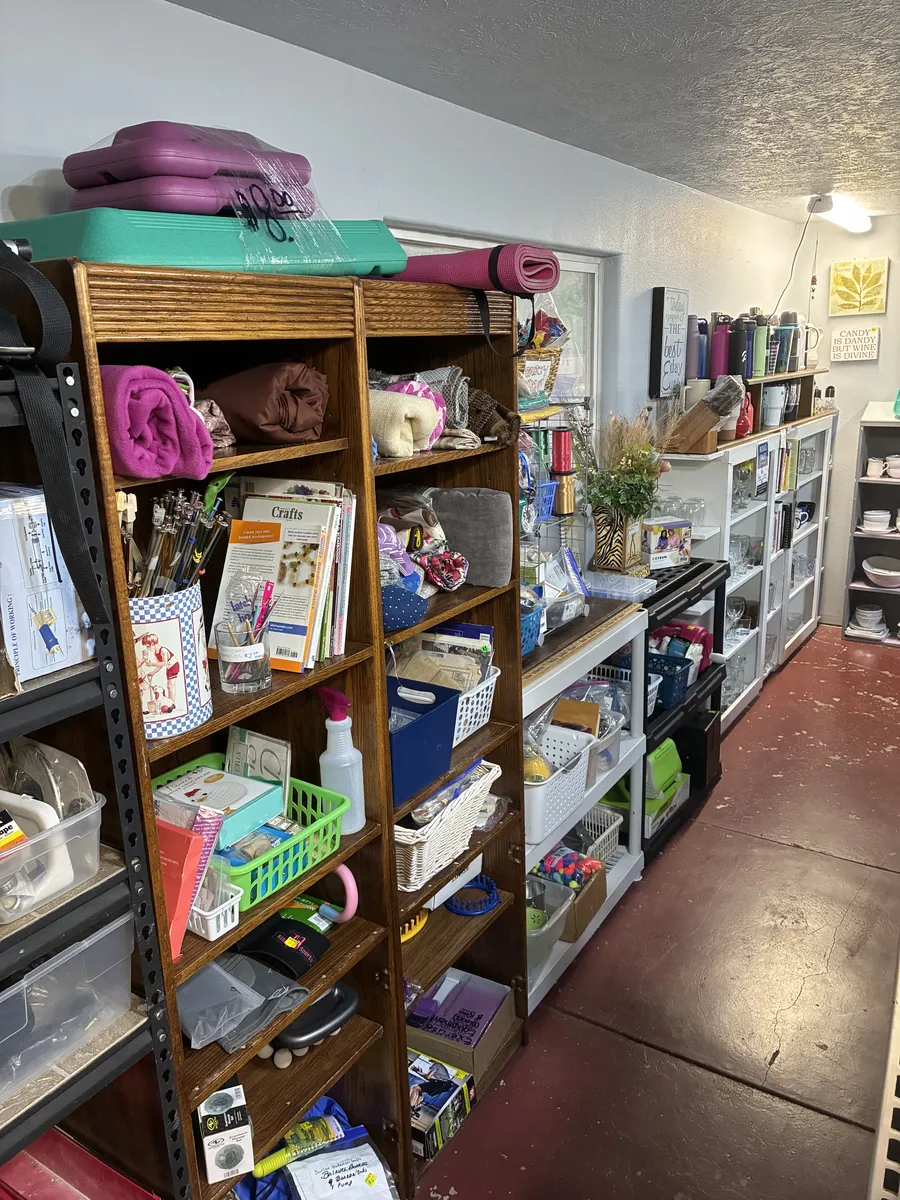 Shelves of small household items, towels and rolled mats at BAM Thrift store